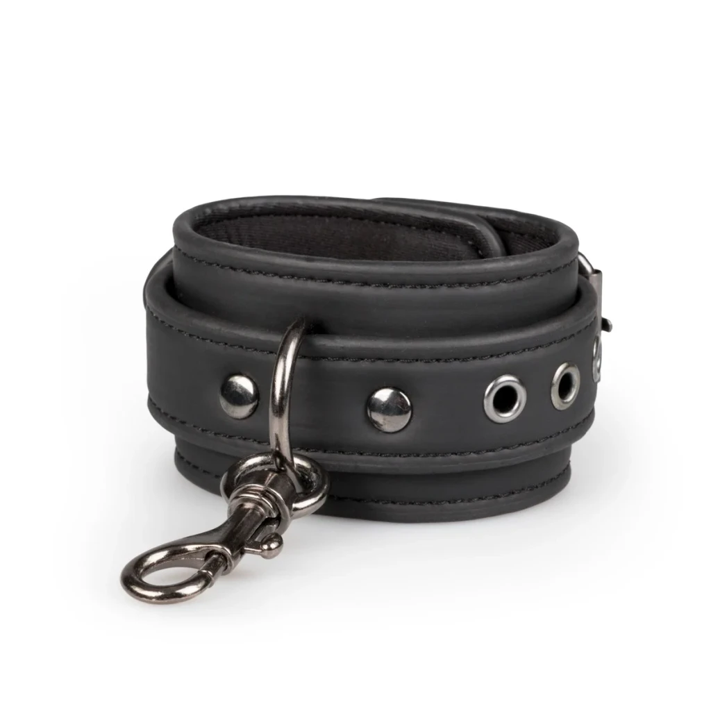 Close-up of a black leather cuff showing stitched edges, metal eyelets, an attachment ring and a silver-tone swivel connector clip.