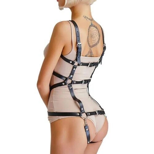 Rear view of black leather full body harness over beige clothing, with buckled shoulder straps, horizontal back bands and lower clip attachments.