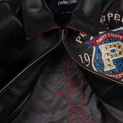 Women's black leather anniversary bomber jacket, open front and lining, with red and blue crest artwork and decorative gold-toned accents.