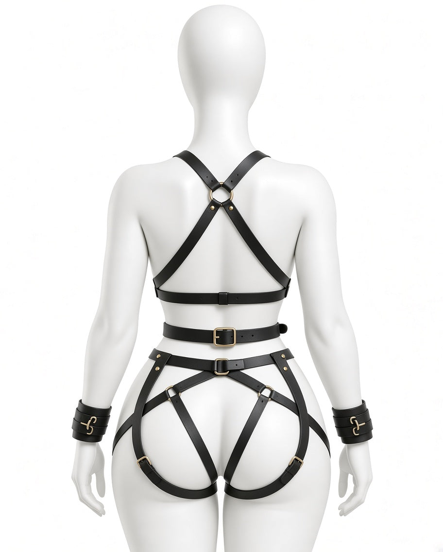 Rear view of women’s black leather harness set showing ring-connected shoulder straps, waist belt, adjustable hip and thigh straps and wrist cuffs.