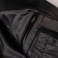 Women's black leather varsity jacket, interior zip pocket, showing contrasting cream accents and decorative details in the supplied product photograph.