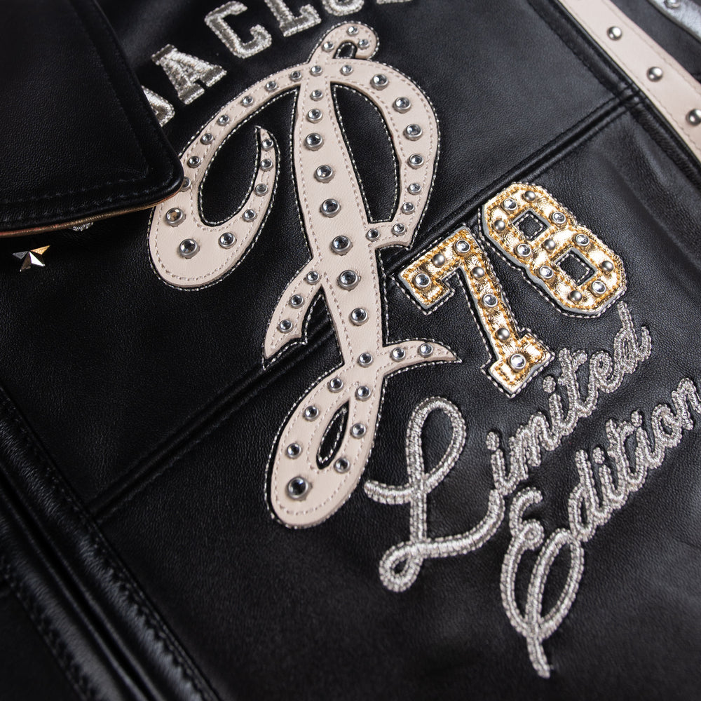 Women's black leather varsity jacket, chest lettering close-up, showing contrasting cream accents and decorative details in the supplied product photograph.