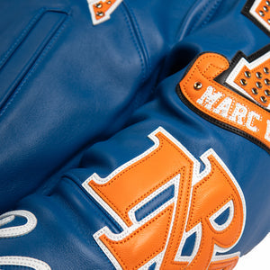 Women's blue and orange leather varsity jacket, sleeve letter detail, showing New York basketball graphics and contrasting decorative details.