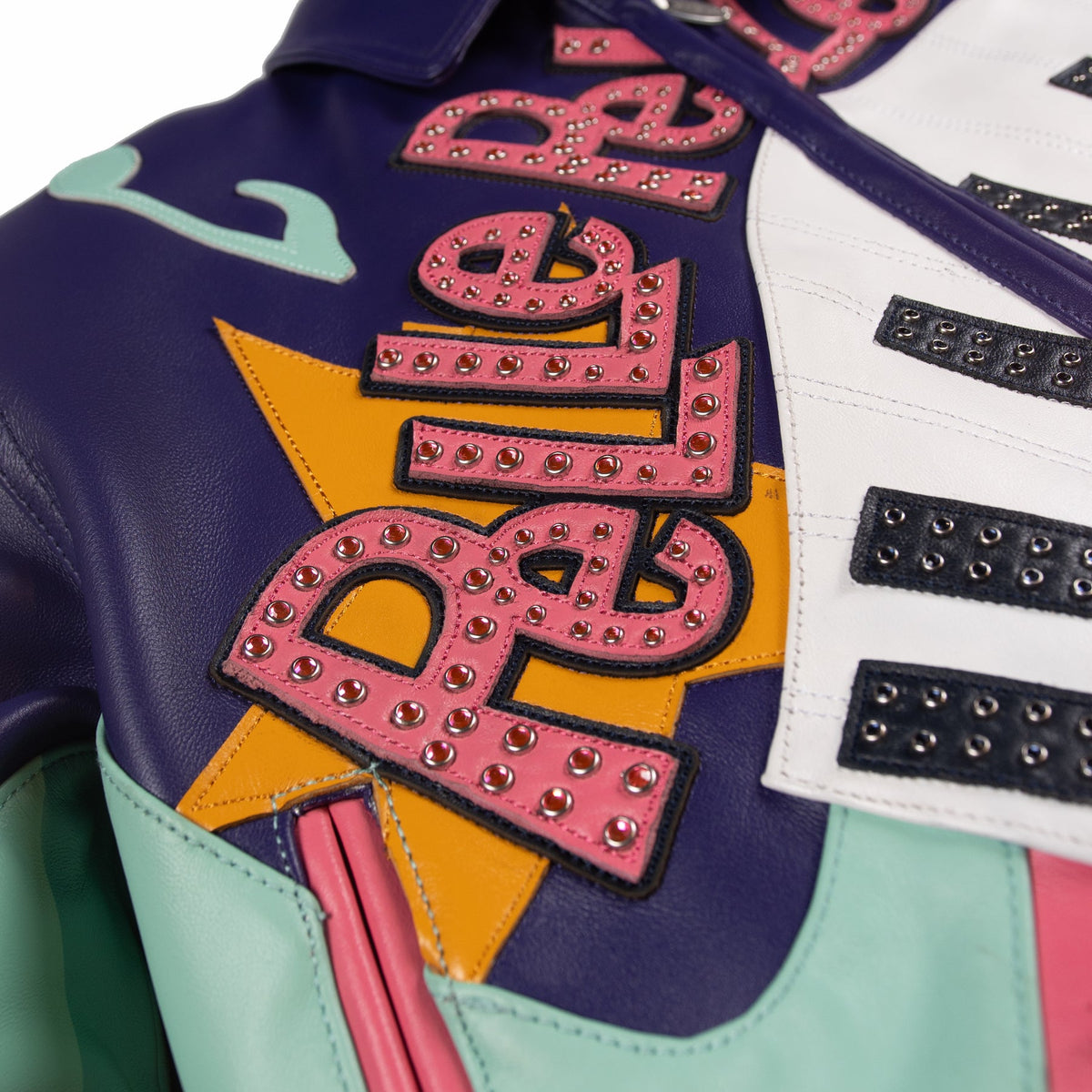 Front detail of a multicolor leather music jacket showing studded pink lettering, yellow star applique and black-and-white piano-key motif.