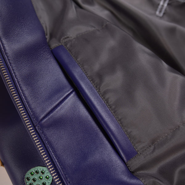 Close-up of the inner pocket on a multicolor leather music jacket showing dark fabric lining, stitched edges and purple front zip facing.