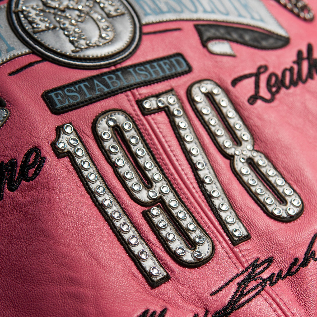 Women's pink and black leather varsity jacket, back number detail, featuring contrast panels and decorative lettering in the product photo.