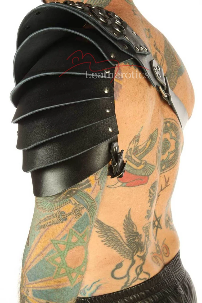 Black leather layered shoulder armor harness, side view showing curved overlapping panels, metal rivets and a lower fastening strap.