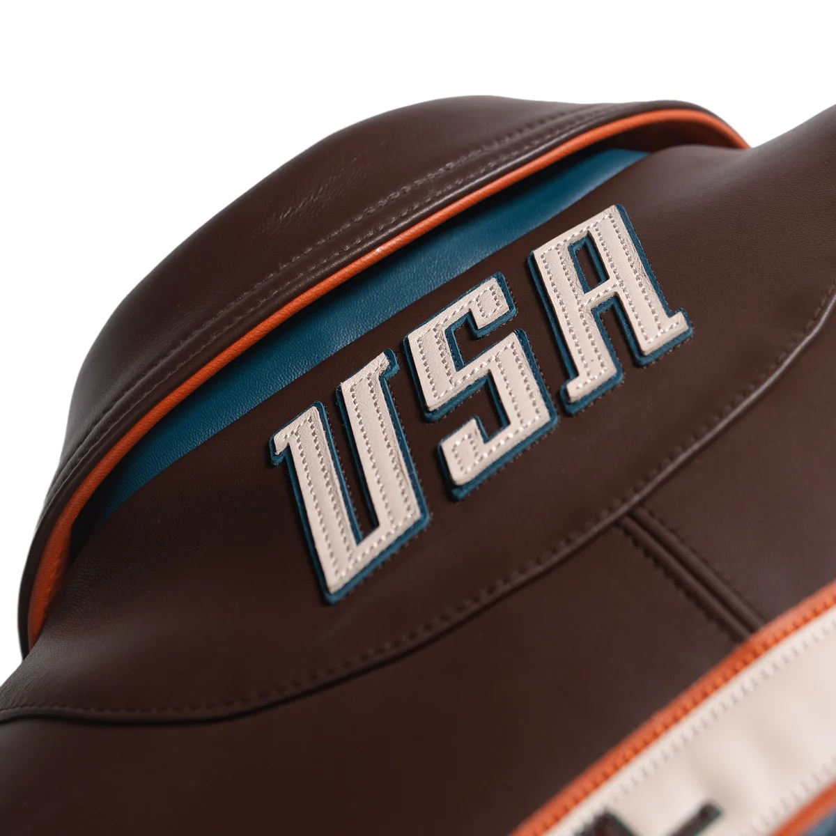 Close view of the brown leather jacket's back collar showing stitched USA lettering, teal underlay, orange piping and shaped seams.
