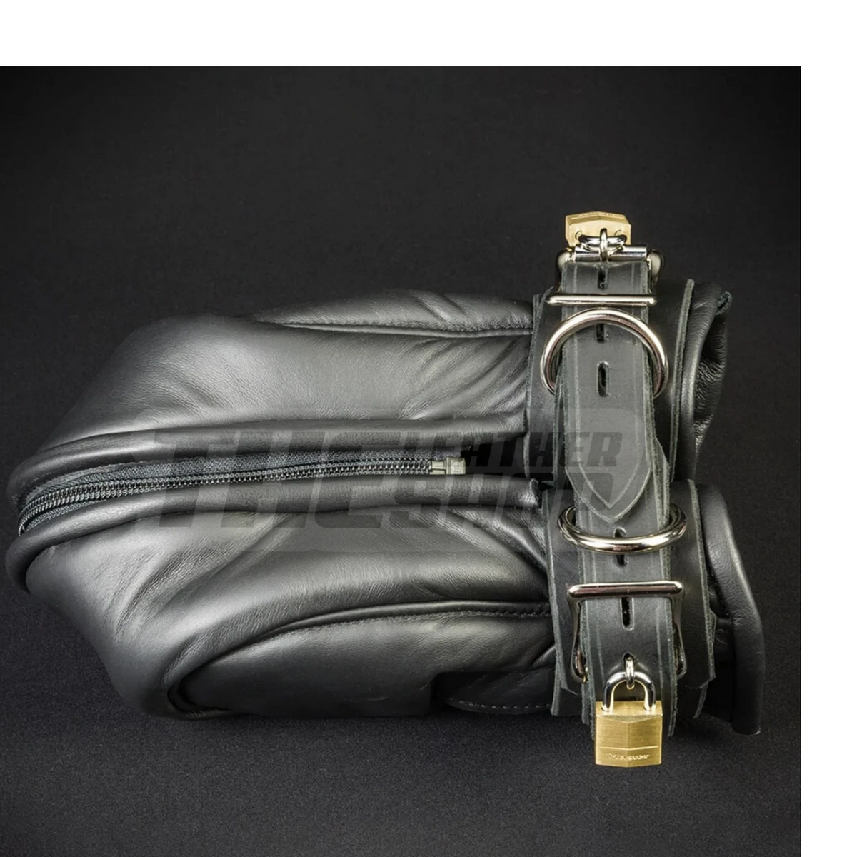 Black leather closed mitt showing a long zipper, adjustable wrist strap, silver-tone D-rings and buckles against a dark background.
