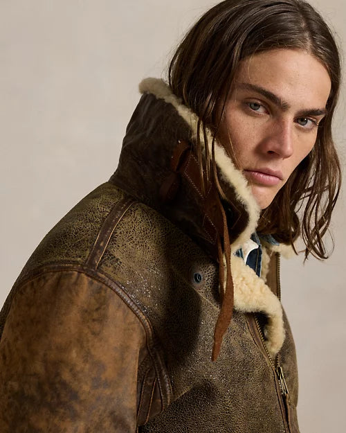 Men's brown genuine leather aviator jacket with raised cream-trimmed collar, throat strap and contrasting distressed shoulder panels.