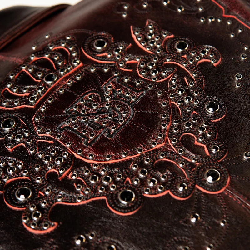 Close-up of the Pelle Pelle Shoulder Crest jacket showing a crowned appliqué, red outlines, ornate scrollwork and metallic studs.
