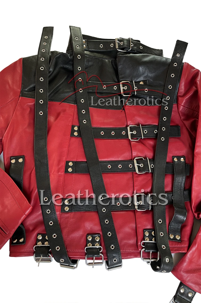 Red and black leather straitjacket laid flat, showing rear buckle fastening straps, metal eyelets, riveted tabs and long leather straps.