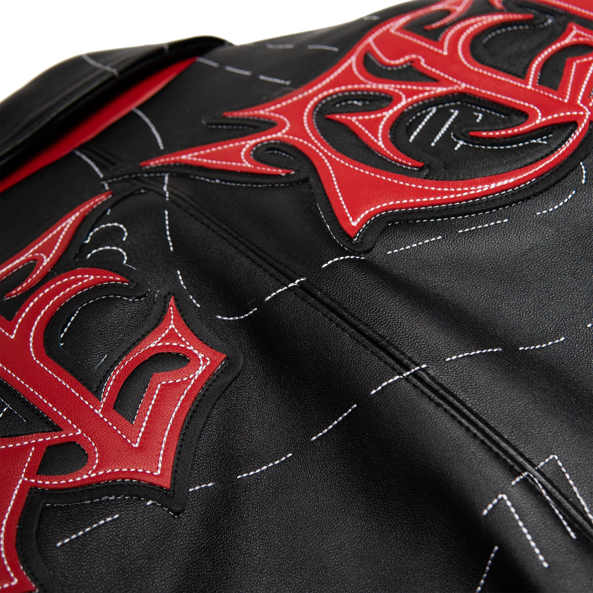 Women's black leather contour stitch bomber jacket, close-up of red shoulder lettering with white edge stitching and curved line details.