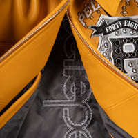 Open front detail of yellow genuine leather jacket showing dark patterned lining, zipper teeth and embellished chest crest applique.
