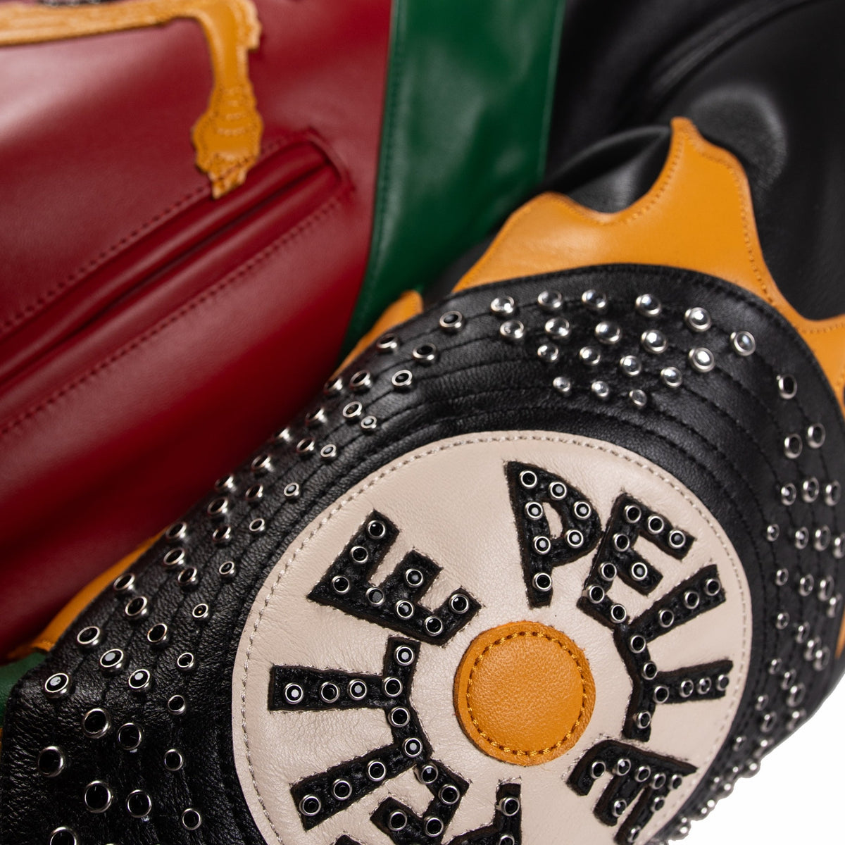 Record-inspired sleeve patch on leather music jacket with ivory center, black lettering, metal eyelets and yellow flame-like edging.