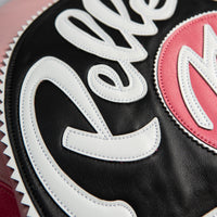 Detail of white script applique on black leather jacket panel showing layered lettering, stitched edges and pale pink border accents.