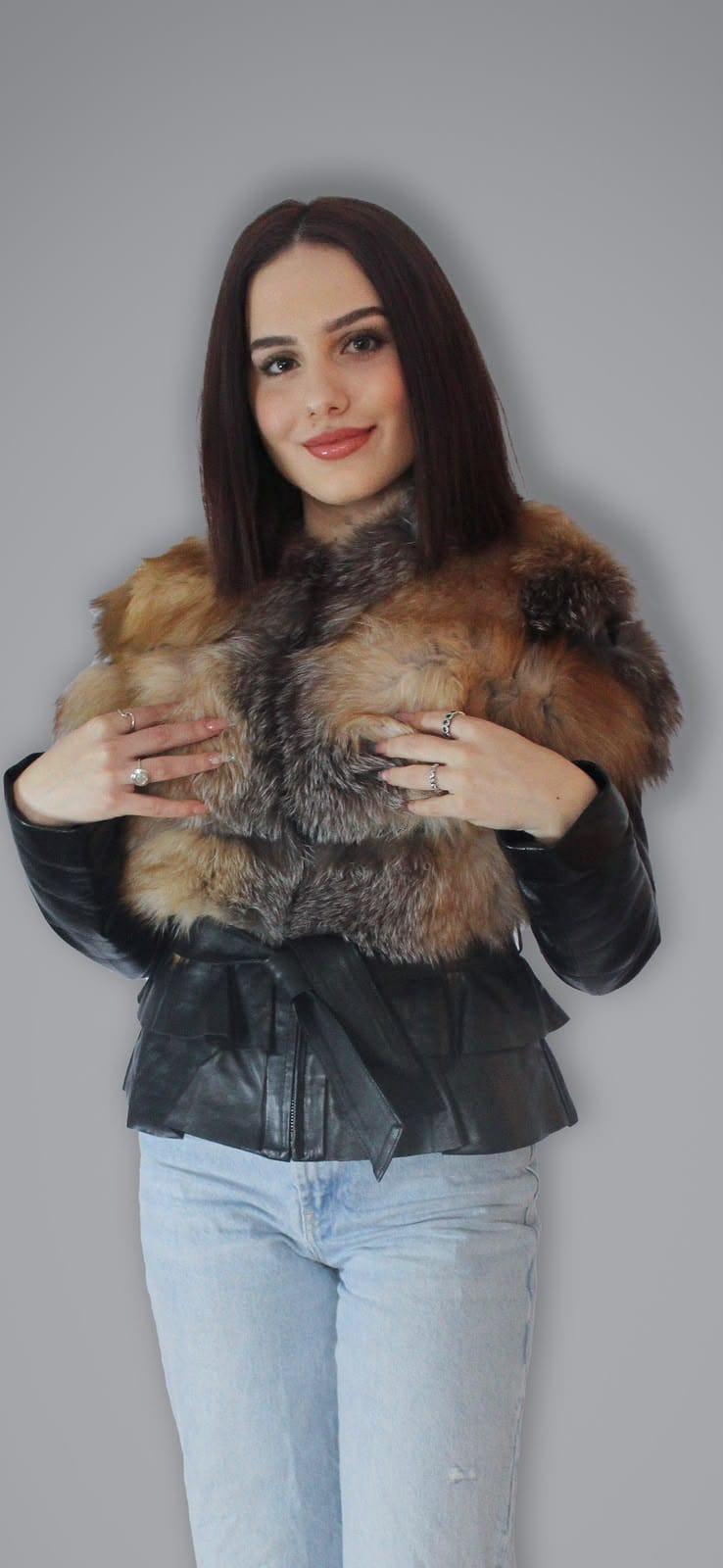 Black leather belted peplum jacket, front view with a broad brown and gray plush collar, matching tie belt, and flared lower panels.