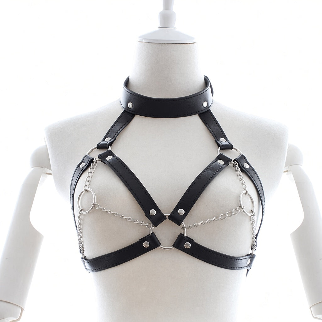 Black leather collar chest harness front view with V-shaped straps, silver-tone chains, rivets and circular rings on a white mannequin.