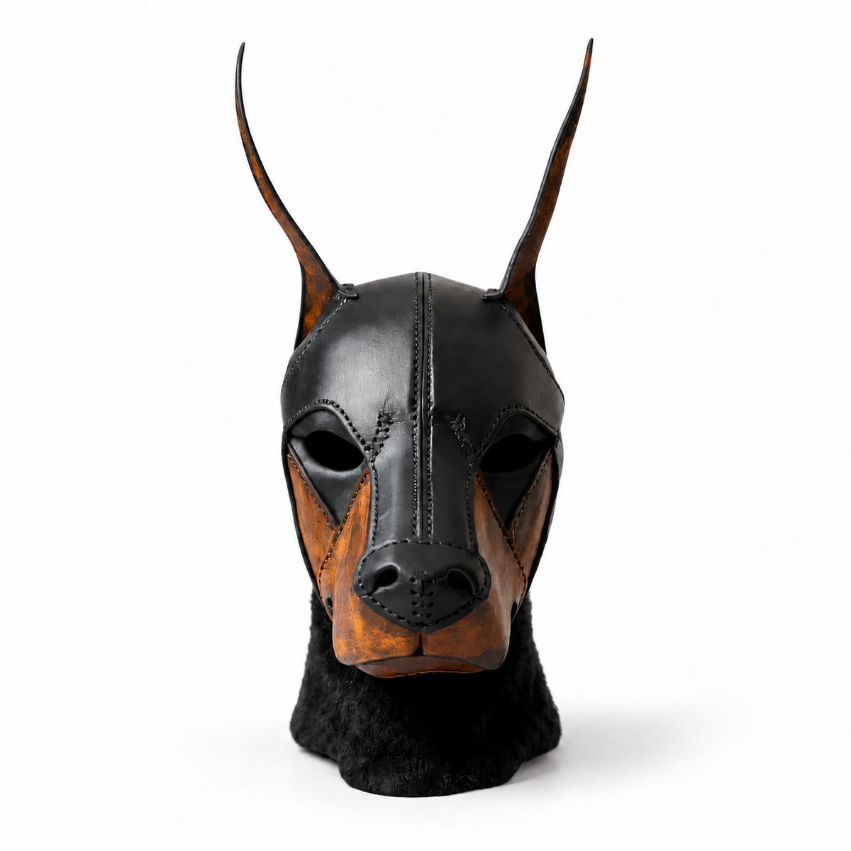 Front view of a black and brown leather canine mask with tall pointed ears, open eye cutouts, a shaped muzzle and visible stitched panels.
