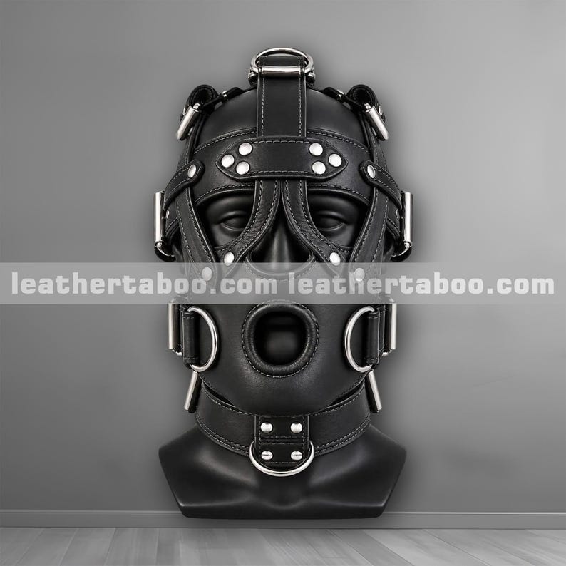 Black leather hood mask front view showing eye and mouth openings, forehead strap and jaw buckles
