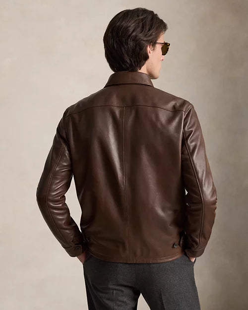 Rear view of men's chocolate brown leather jacket showing the shoulder yoke, central vertical seam, button cuffs and rear waist tabs.