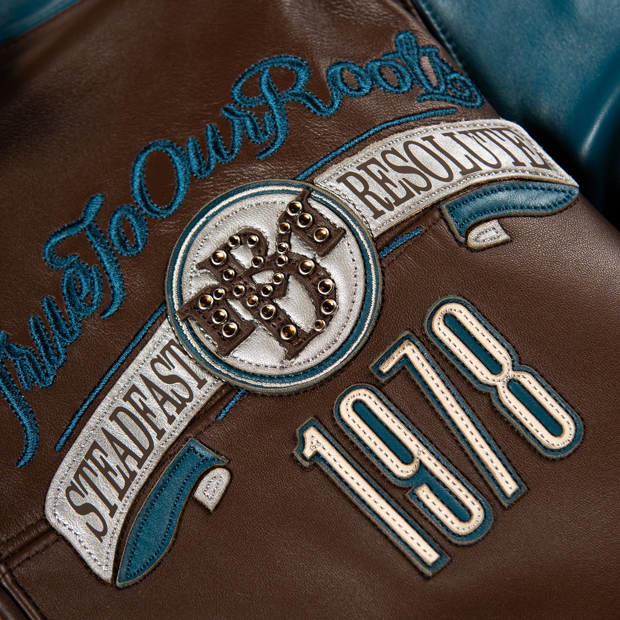 Studded back panel of brown and teal leather jacket with Steadfast Resoluts banner, crest and 1978 numerals