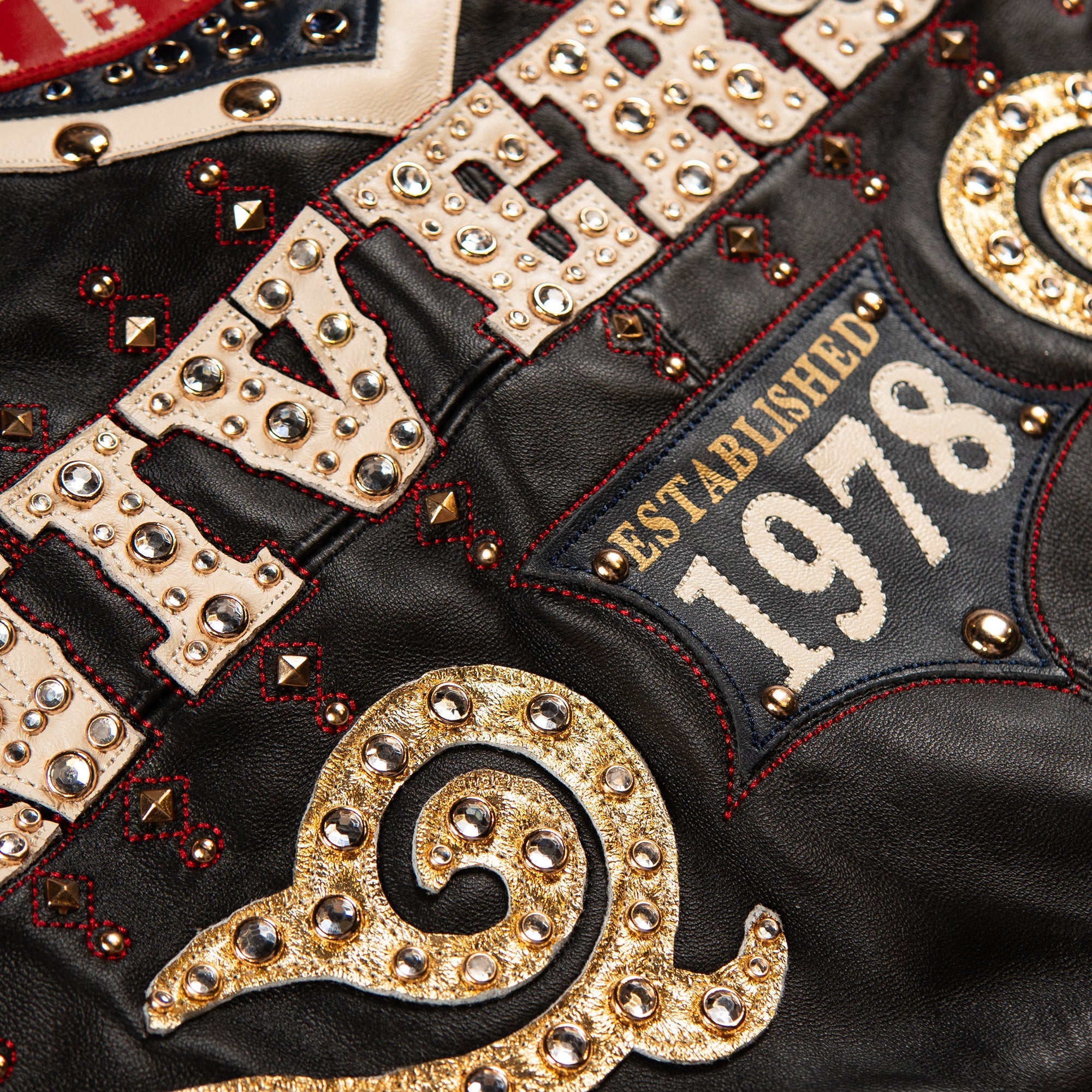 Back view of a black leather jacket featuring Pelle Pelle lettering, a large 48 anniversary crest and red banner details