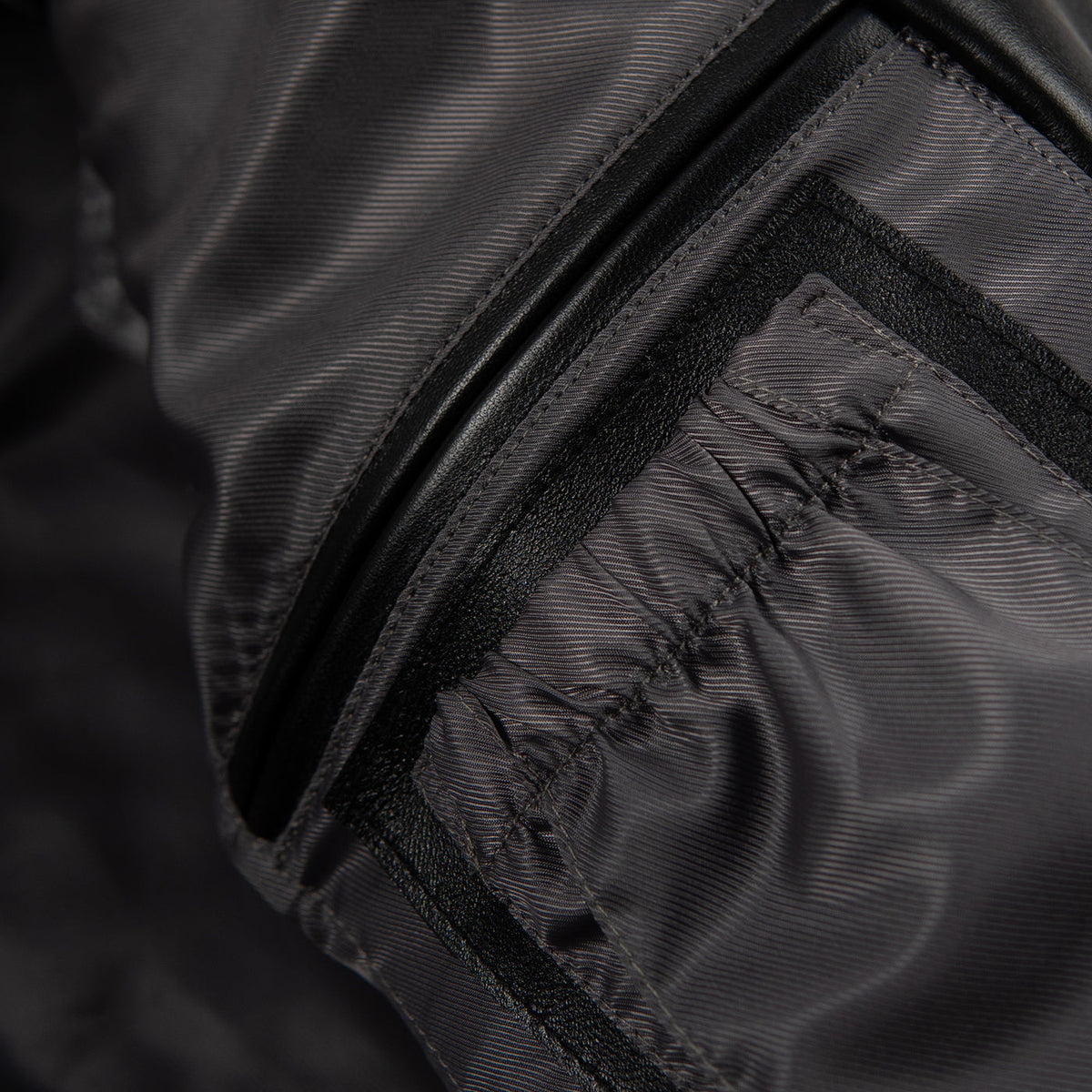 Women's black leather anniversary bomber jacket, interior pocket detail, with red and blue crest artwork and decorative gold-toned accents.