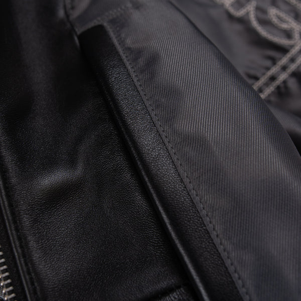 Women's black leather varsity jacket, lining close-up, showing contrasting cream accents and decorative details in the supplied product photograph.