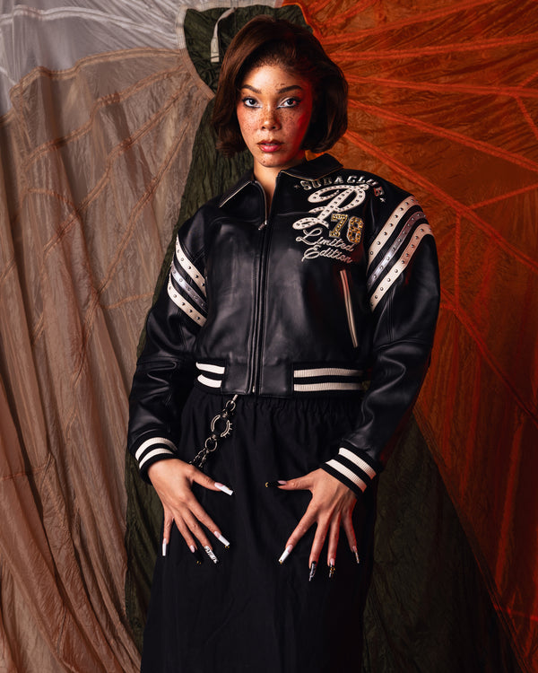 Women's black leather varsity jacket, styled model view, showing contrasting cream accents and decorative details in the supplied product photograph.