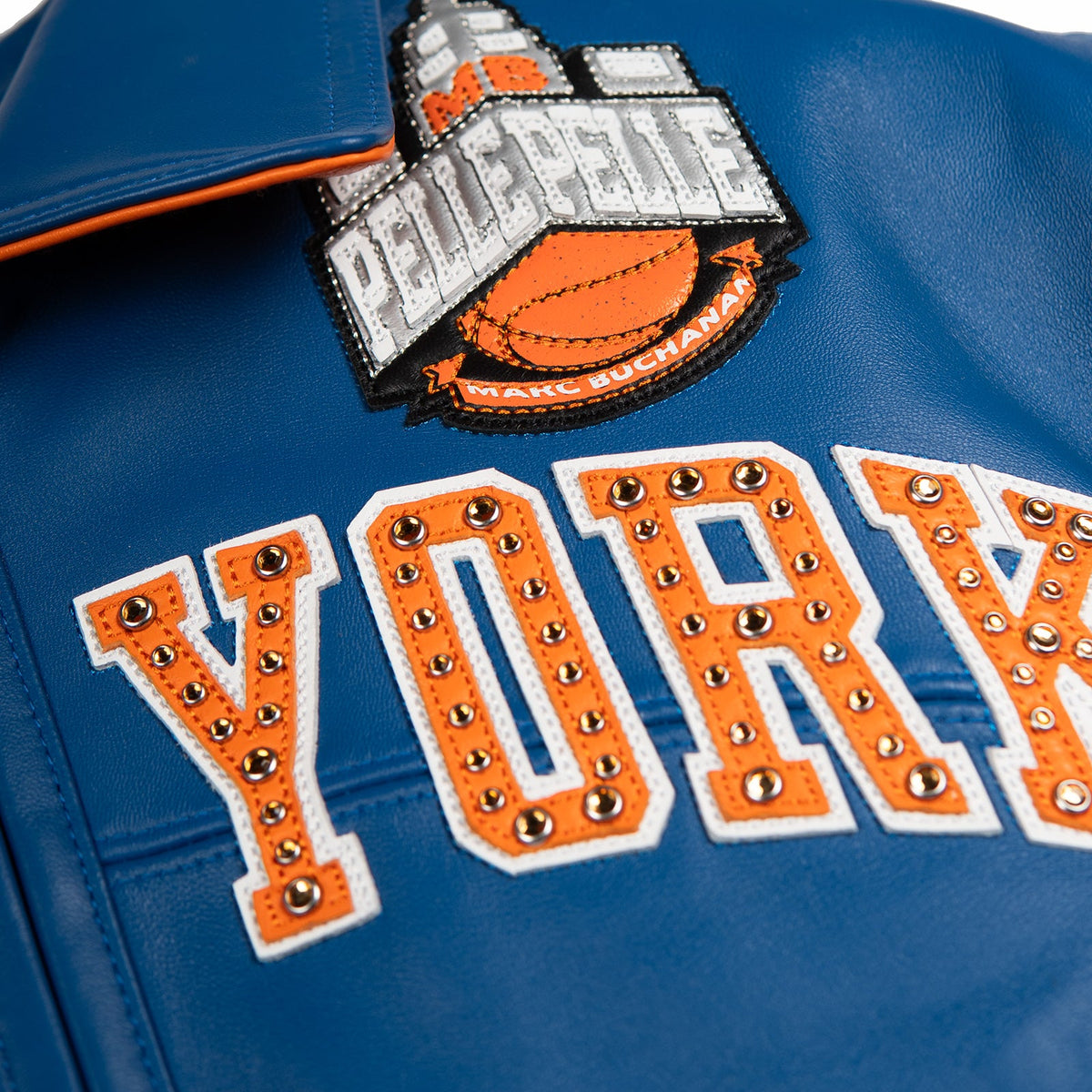 Women's blue and orange leather varsity jacket, chest lettering detail, showing New York basketball graphics and contrasting decorative details.