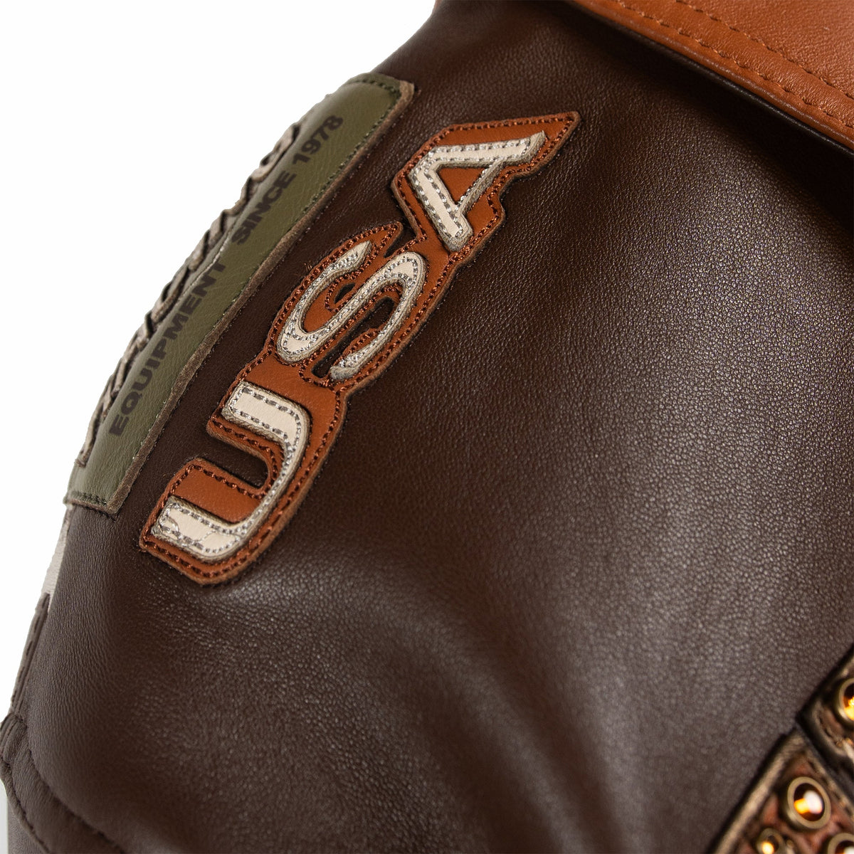 Women's brown colorblock leather racing jacket, shoulder lettering detail, with caramel and olive panels and decorative metallic accents.