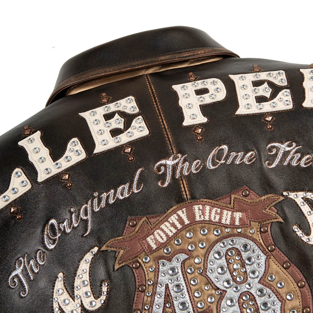 Women's distressed brown leather anniversary jacket, upper back lettering detail, with cream lettering, layered crest artwork, and reflective embellishments.