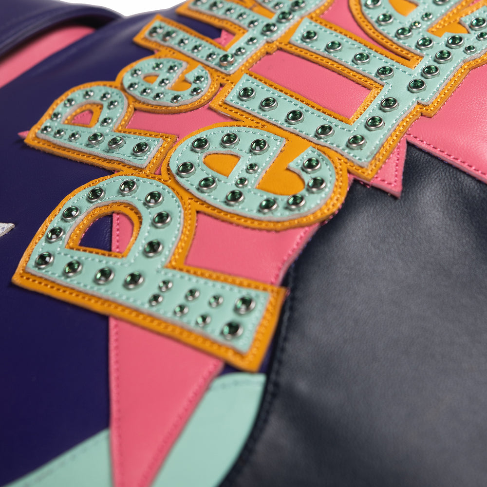 Back lettering detail of a multicolor leather music jacket showing mint appliques with reflective studs over pink and yellow star panels.