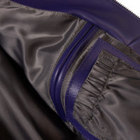 Interior detail of a multicolor leather music jacket showing dark fabric lining, stitched pocket construction and purple leather edging.