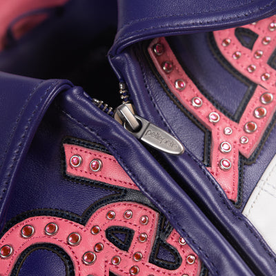 Close-up of a multicolor leather music jacket zipper pull beside the purple collar and raised pink lettering with reflective embellishments.