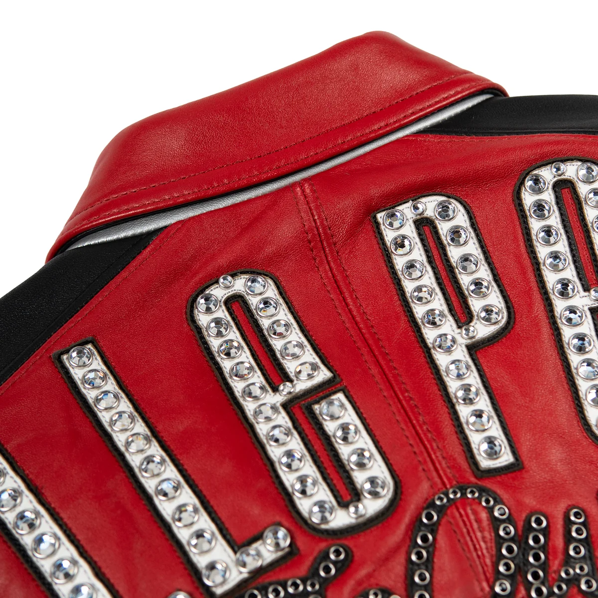 Women's red and black leather varsity jacket, upper back lettering close-up, with contrasting panels, embroidered motifs, and reflective embellishments.