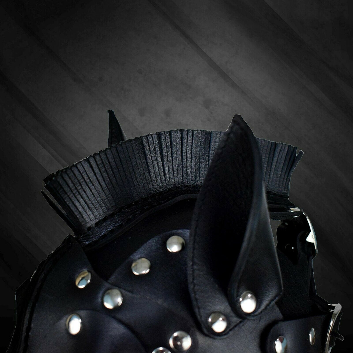 Top detail of black leather horse mask showing the cut leather fringe mane, pointed ear, layered panels and silver-tone rivets.