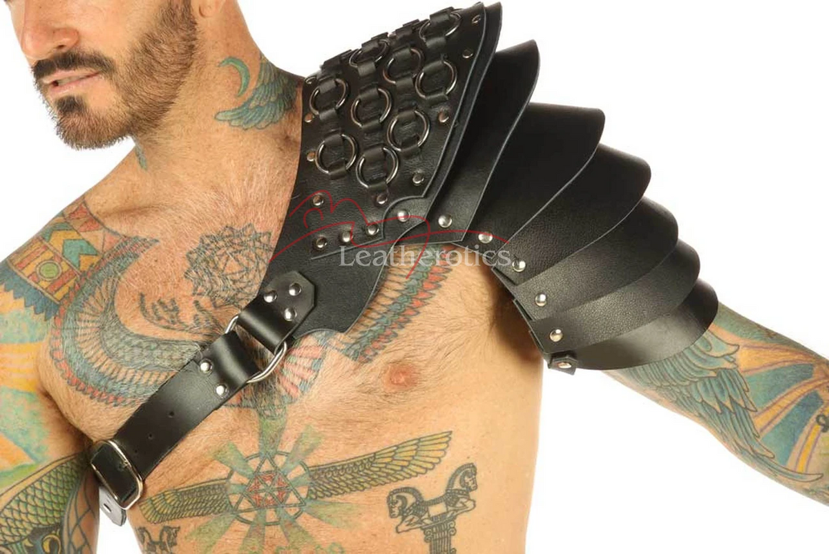 Black leather layered shoulder armor harness, close front view showing ring details, riveted panels and an adjustable chest buckle strap.