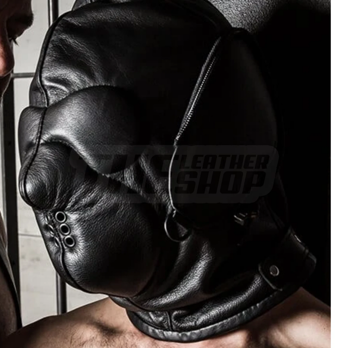 Close view of a black leather hood showing shaped nose panel, covered eye section, small metal eyelets and a rounded lower face panel.