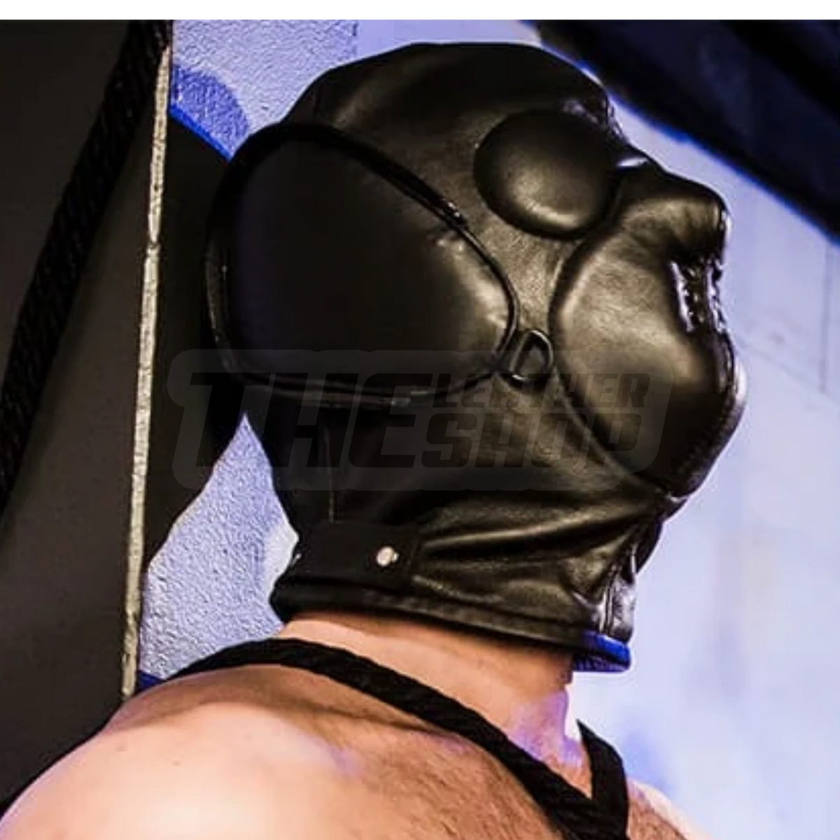Side view of a black genuine leather hood showing raised eye cover, shaped face panel, metal eyelets and a fitted neck section.