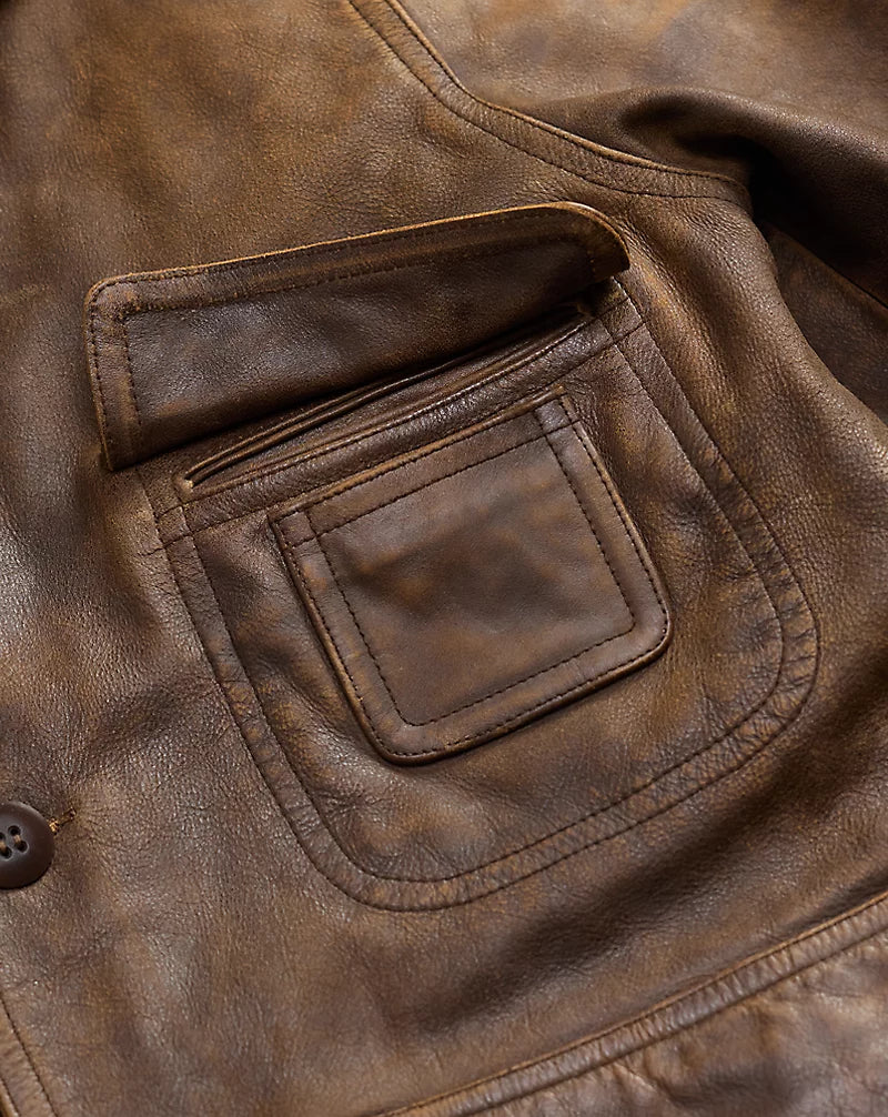 Close-up of the chest pocket on a distressed brown leather jacket, showing its flap, layered pocket panel and contrasting stitching.