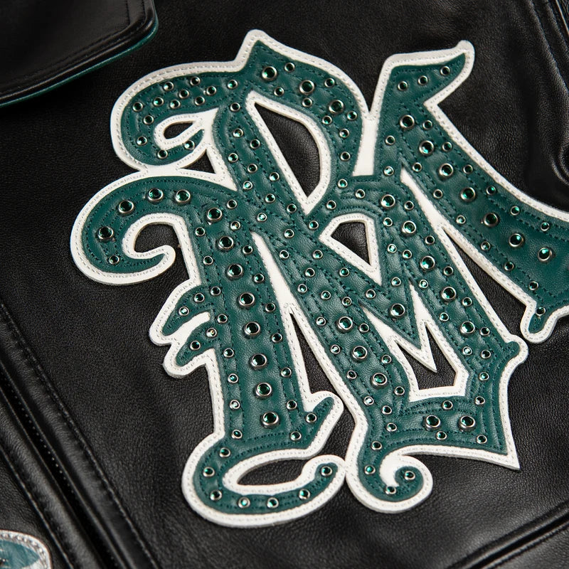 Close-up of the green monogram on a black Pelle Pelle All Time Champions Jacket, showing white edging and round embellishments.