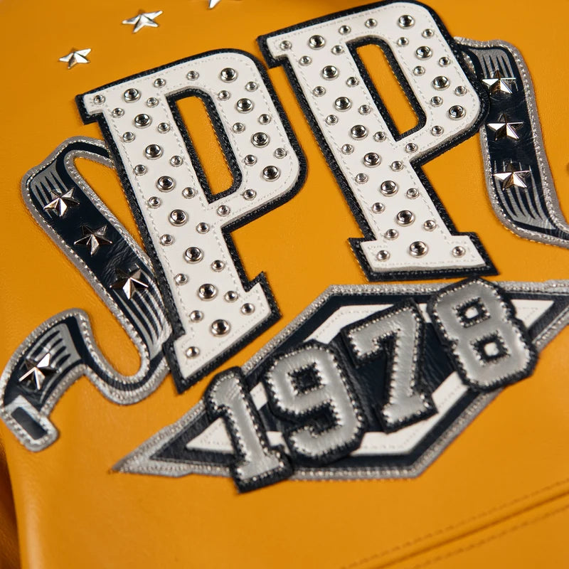 Close-up of white PP lettering and a 1978 patch on the maize Pelle Pelle All Time Champions Jacket, with round details and star studs.