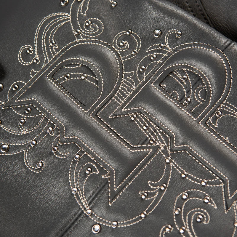 Close-up of gray Pelle Pelle Shoulder Crest jacket showing raised monogram leather applique, contrast stitching and metal studs.