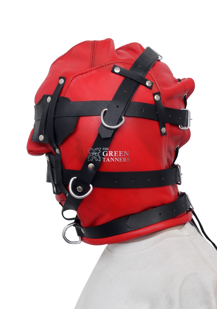 Side view of red leather full-face hood showing black adjustable buckle straps, silver-tone D-rings and stitched leather panels.
