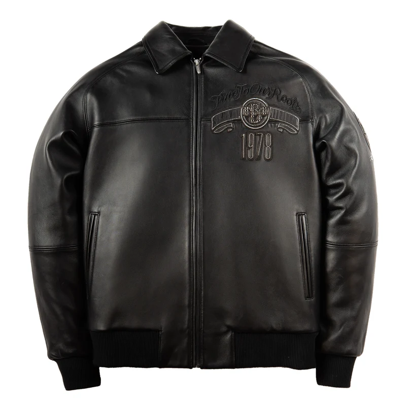 Front of black True To Our Roots leather jacket with pointed collar, zip closure, chest emblem and ribbed cuffs