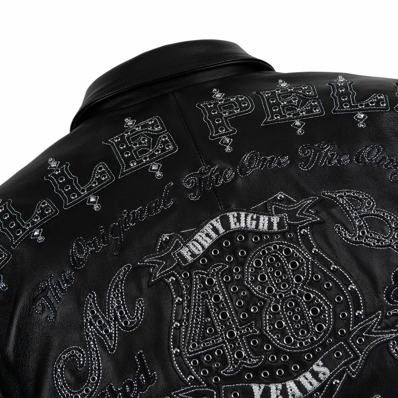 Upper back detail of black genuine leather jacket showing tonal arched lettering, large 48 crest, decorative eyelets and metallic stitching.