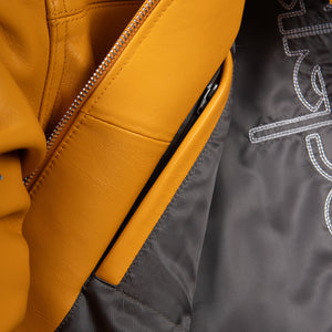 Interior of maize yellow leather jacket showing dark lining, leather facing and a leather-trimmed vertical zip pocket opening.