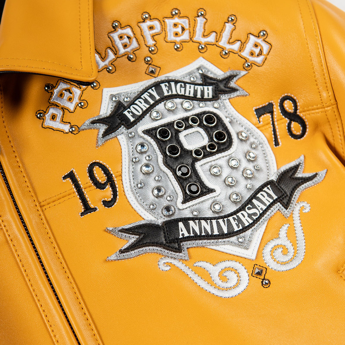 Chest crest on yellow leather jacket with layered black, white and silver-tone applique, decorative stones and embroidered numbers.